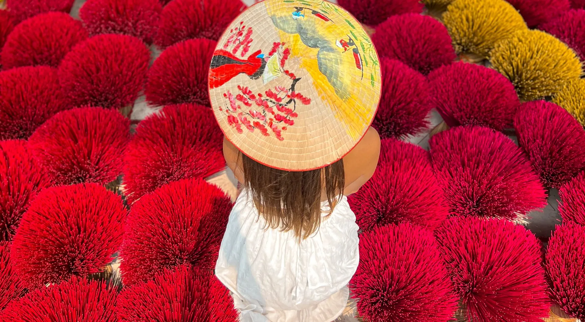 Vietnam, Isabel mit vietnamesischem Hut zwischen Räucherstäbchen in Hoi An